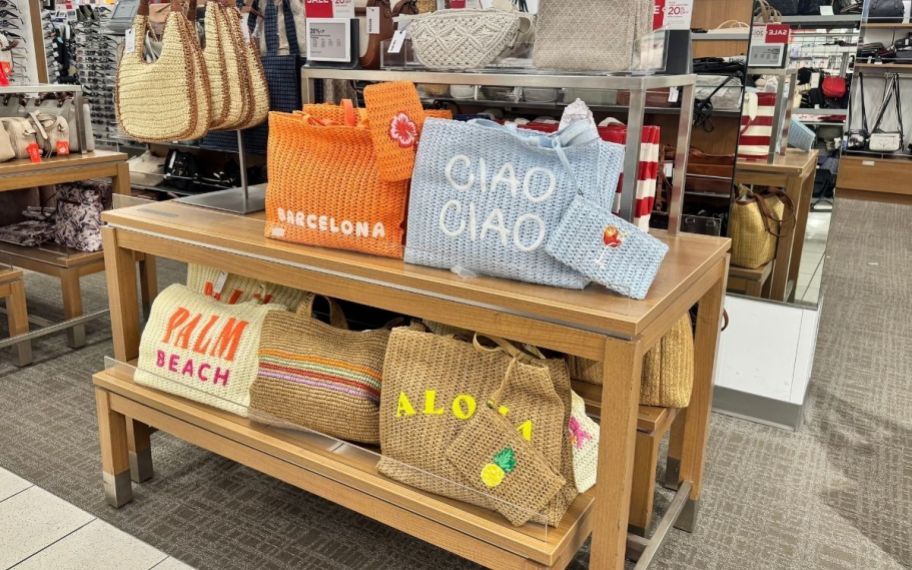 woven straw beach bags in various designs on a display table in a Kohl's store