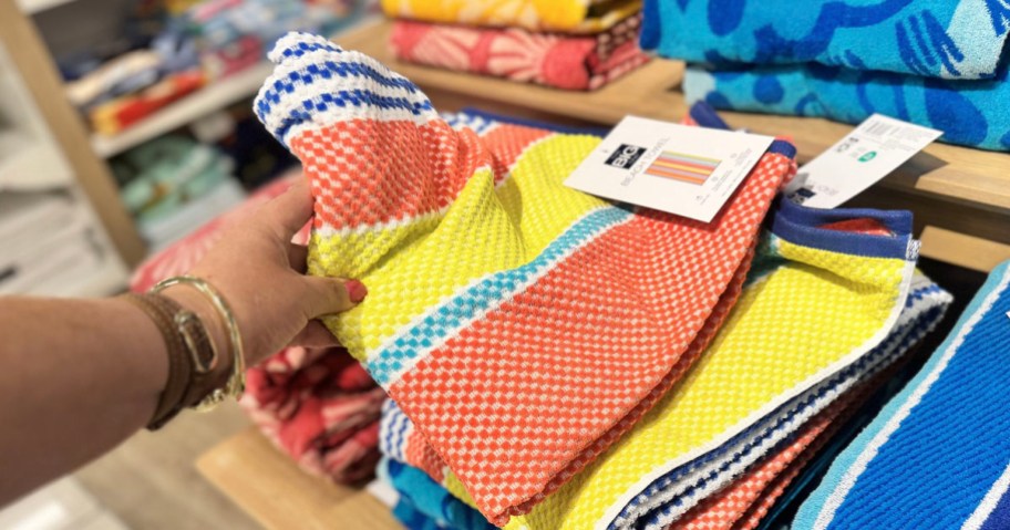 hand reaching for big one beach towels on shelf