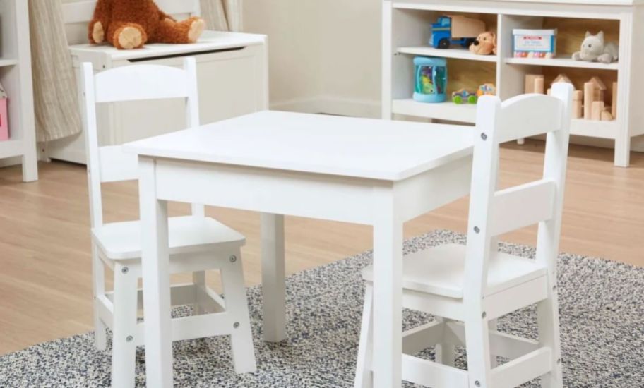 a kid-sized white wooden table and two chairs in a playroom