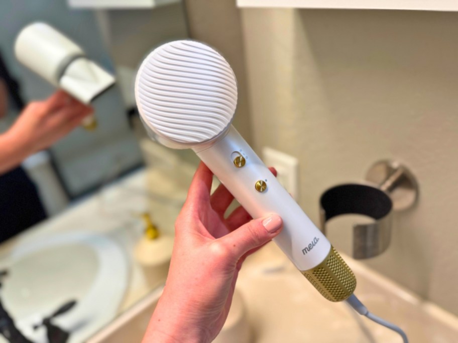 woman's hand holding a white and gold ionic hair dryer