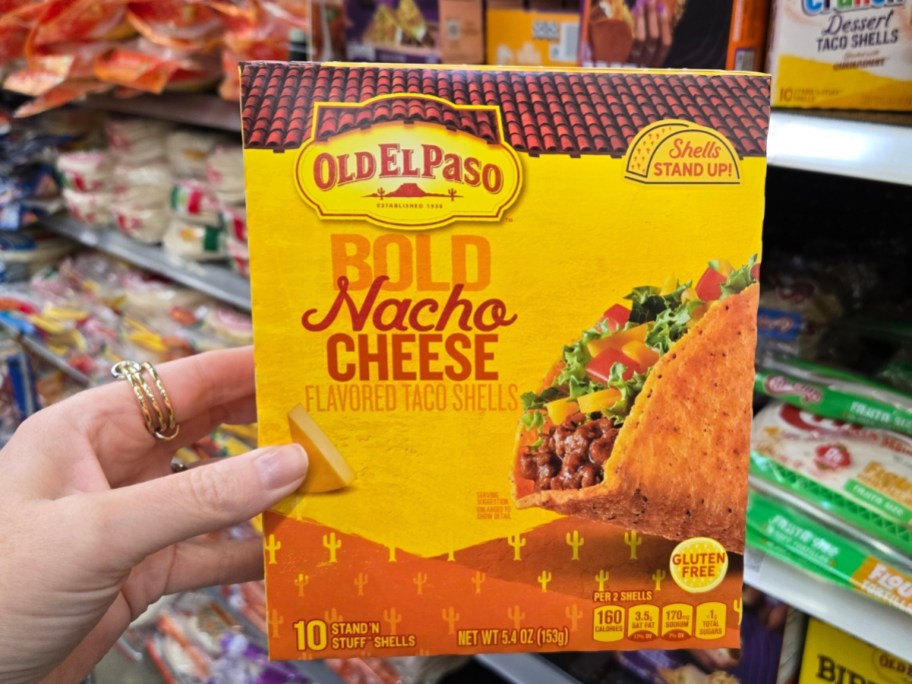 hand holding a box with Old El Paso Stand 'N Stuff Bold Nacho Cheese Flavored Taco Shells