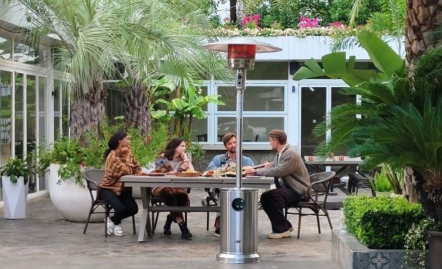 a patio heater on a patio with a table of 4 people in the background