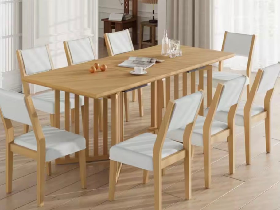 wooden dining table with magazines and cups on top 