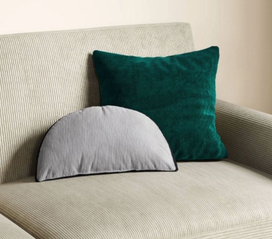a half moon shaped pillow shown with a square pillow on a sofa