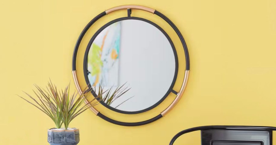 black and wood circular mirror hanging on yellow wall 