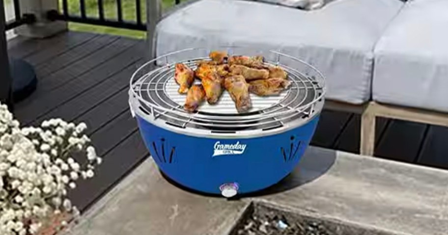 blue grill with chicken legs on top of table