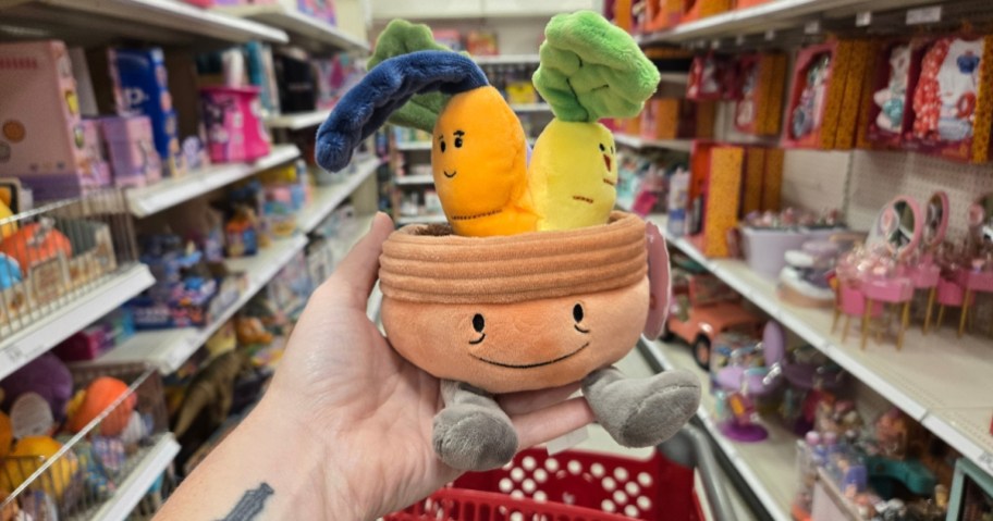 hand holding a plush toy that looks like a planter with veggies in it