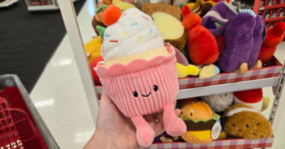 hand holding a cupcake plush, display with more plush behind it