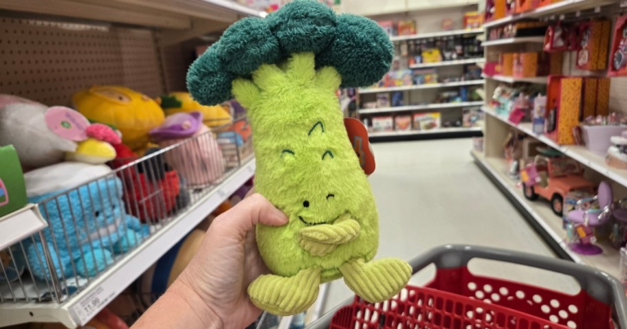 hand holding a broccoli plush toy in a store