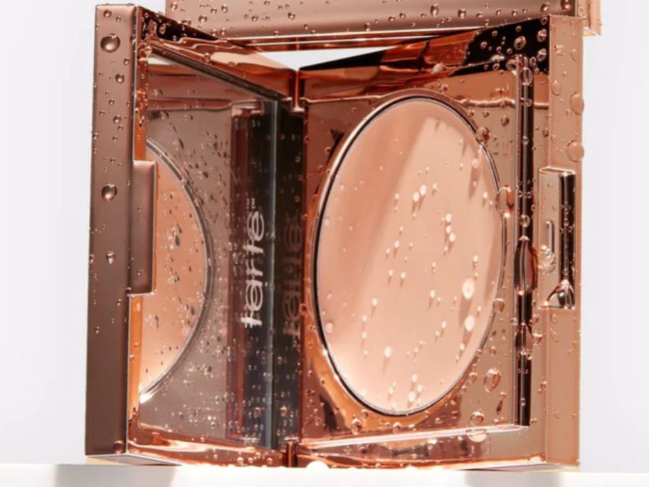 An open compact of tarte CC under eye concealer covered in beads of water