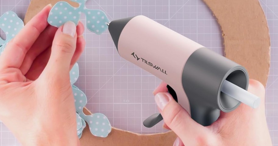 person using a pink glue gun to make a craft