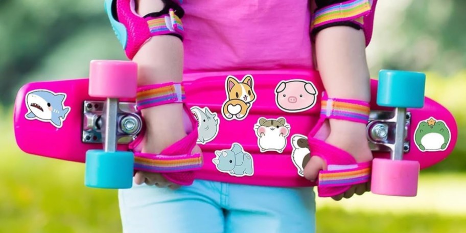 child holding pink skateboard with vinyl animal stickers on it 