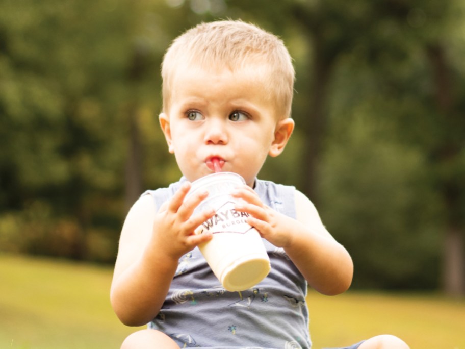 baby drinking a milkshake outside