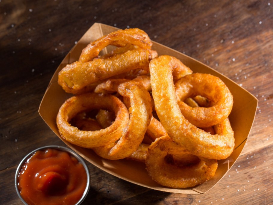 onion rings in a paper holder next to ketchup