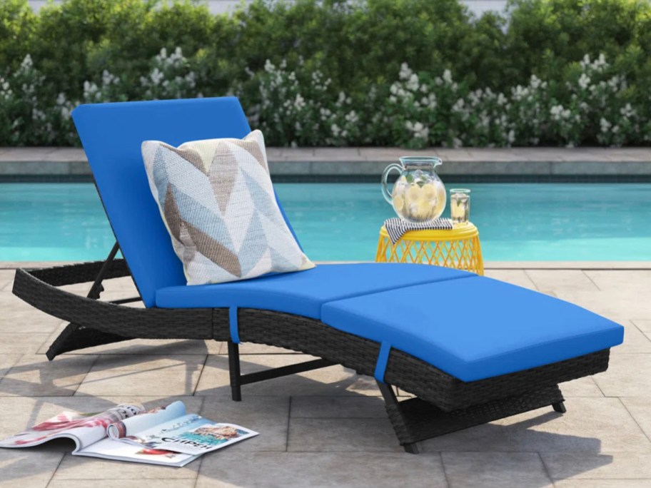 black lounge chair with blue cushion next to pool 
